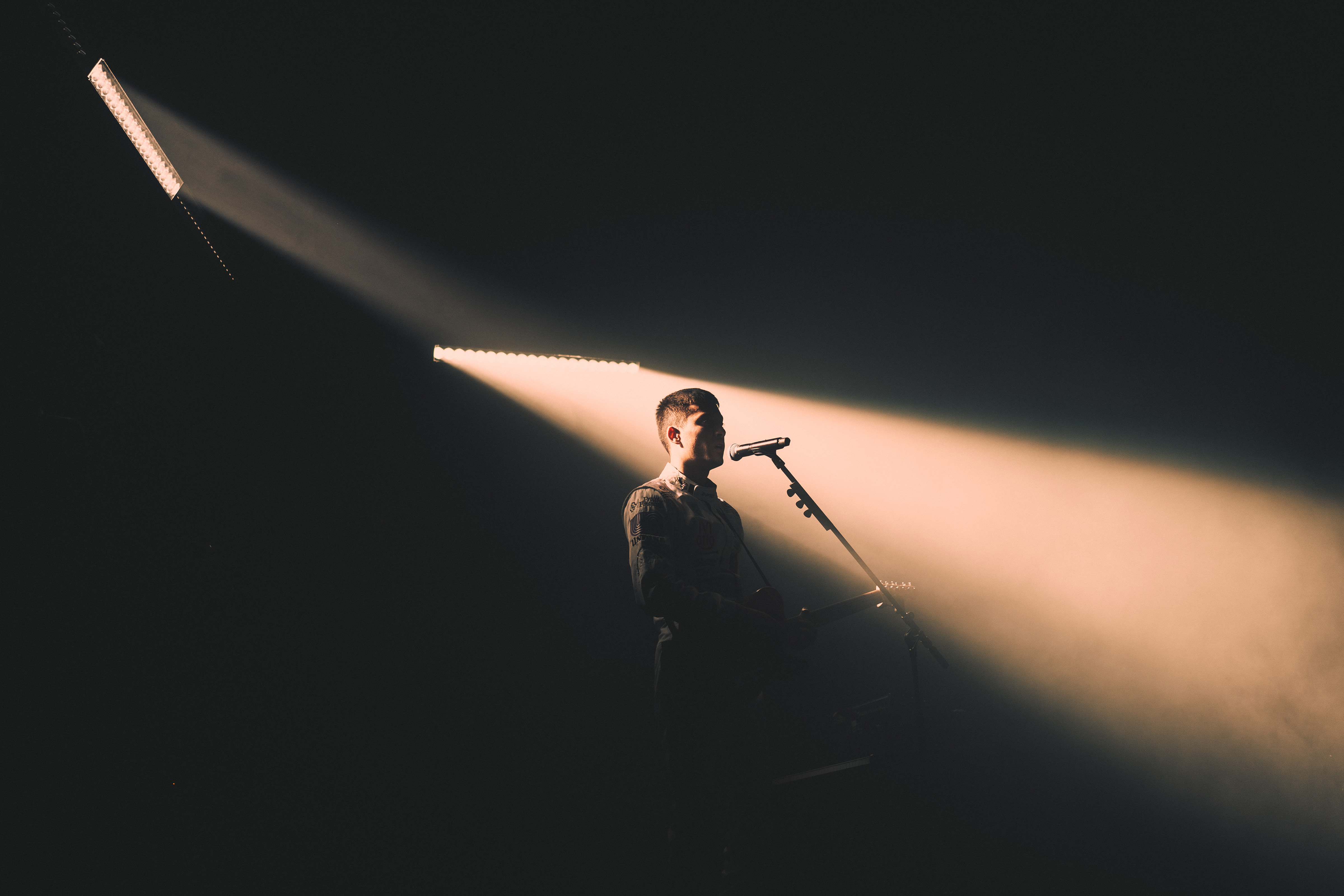 music artist eden singing on a dark stage dramatically backlit by two spotlights